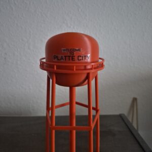 3D printed Platte City Missouri water tower replica with bright orange tank and “Welcome to Platte City” lettering on elevated structure