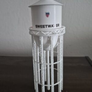 3D printed miniature replica of the historic Sweetwater, Texas water tower with white tank and lattice support legs, featuring “SWEETWATER” lettering and a red Mustang graphic on one side inspired by the Sweetwater Mustangs.