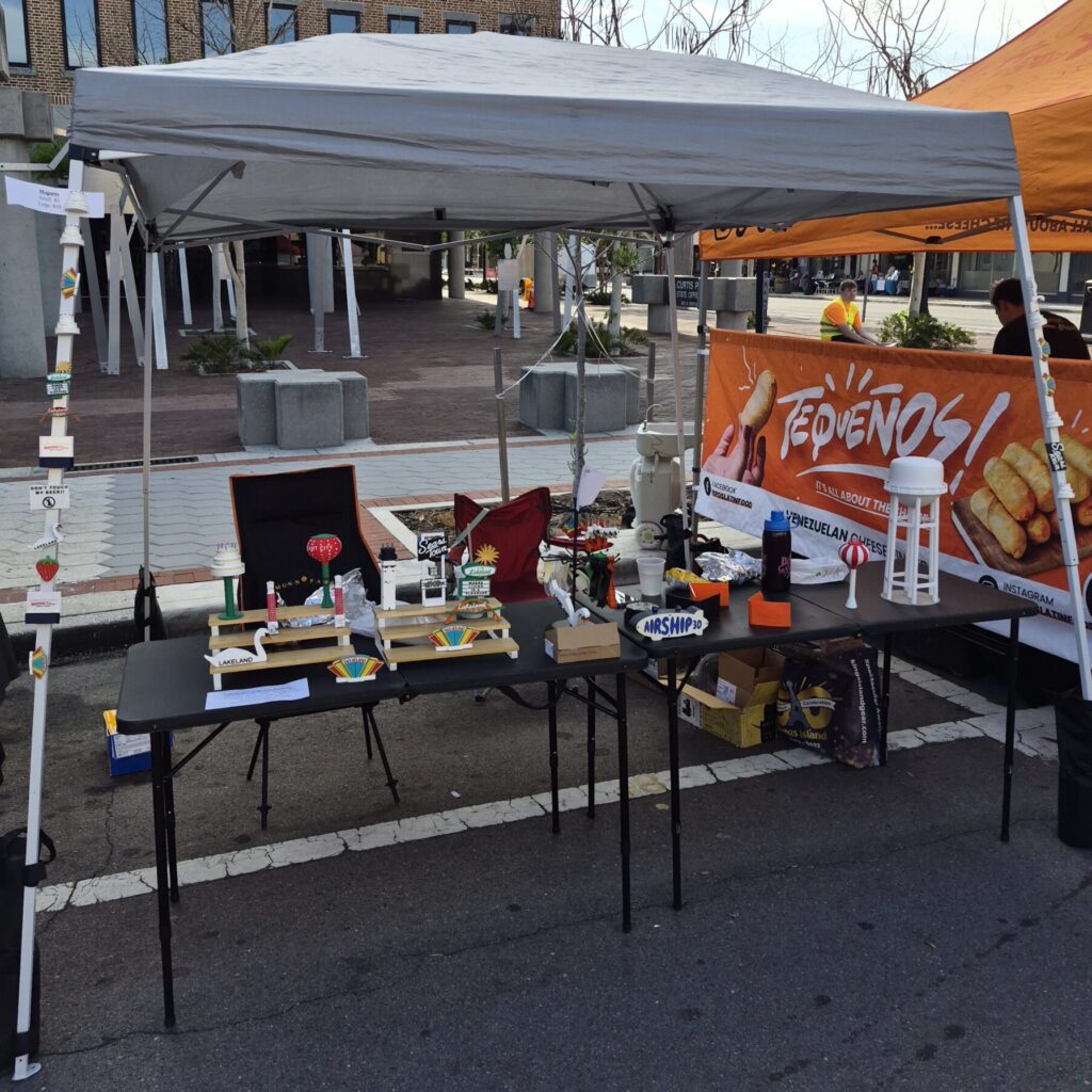 Airship 3D booth at a Lakeland community event featuring 3D printed water towers, local landmarks, magnets, and custom creations.