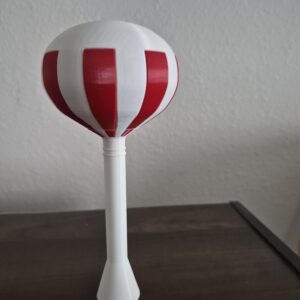 3D printed red-and-white striped spheroid water tower with a sticker-free half-peppermint design, mounted on a white support column and displayed on a tabletop.