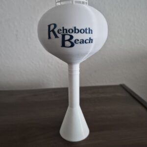 Rehoboth Beach Delaware water tower replica with white spheroid tank, blue Rehoboth Beach lettering, and pedestal support.