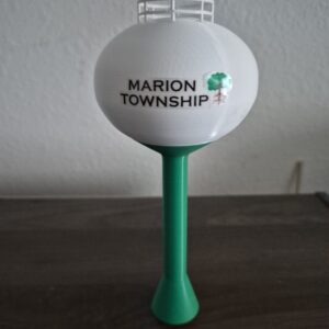 replica of the Marion Township, Michigan water tower with a white tank, green support column, and the Marion Township logo featuring an oak tree.