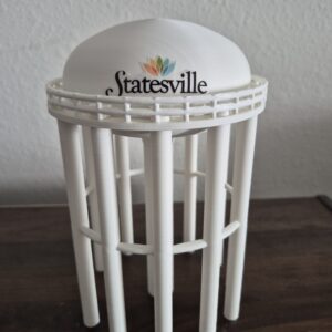 Statesville, North Carolina water tower replica featuring a rounded tank, colorful Statesville logo, circular railing, and multiple support columns.